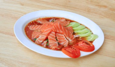 Salmon spicy salad in dish on wood table background.