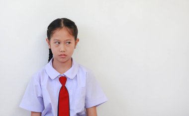 Unhappy with bored face of Asian schoolgirl in school uniform with looking beside on white background. clipart