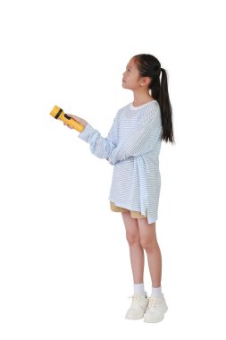 Asyalı kız çocuğu beyaz arka planda el fenerini tutuyor ve boş bir alanda parlıyor. Çocuk ve keşif konsepti. Tam vücut fotoğrafı..