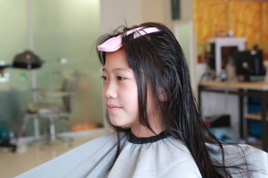 Kuaför kuaförde şirin Asyalı kız çocuğuna saç yapıyor. Kuafördeki genç kız..