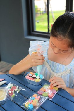 Asyalı kız çocuk kek pişirmeyi, pastayı süslemeyi sever..