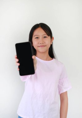 Hafif odaklı gülümseyen Asyalı kız akıllı telefon boş ekranı gösteriyor ve beyaz arka plandaki kameraya bakıyor. Çocuk yüzüne odaklan..