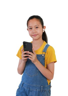 Güzel Asyalı genç kız, beyaz arka planda izole edilmiş akıllı telefon ve kablosuz kulaklıkla müzik dinlemeyi seviyor..