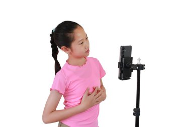 Beyaz stüdyo arka planında izole edilmiş Asyalı genç kız akıllı telefondan canlı yayın yapıyor..