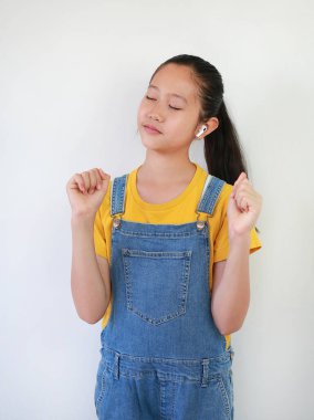 Kablosuz kulaklık kullanan Asyalı bir kızın portresi beyaz arka planda müzikle eğleniyor.