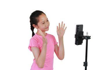 Beyaz stüdyo arka planında izole edilmiş üç ayaklı telefon kullanan Asyalı blogcu kız çocuğu. Sosyal medyada paylaşmak için mobil uygulama üzerinde içerik oluşturan çocuk.