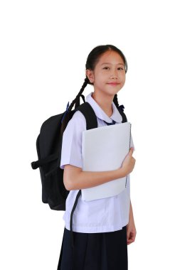 Sırt çantası taşıyan okul üniformalı Asyalı öğrenci portresi beyaz stüdyo arka planında tek başına dururken kitap tutuyor. Kırpma yolu ile resim.