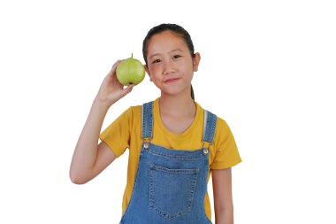 Beyaz stüdyo arka planında izole edilmiş bir guava meyvesinde ısırık izleri gösteren Asyalı genç bir kızın portresi.