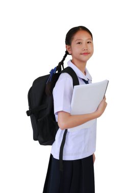 Sırt çantası taşıyan okul üniformalı Asyalı öğrenci portresi beyaz stüdyo arka planında tek başına dururken kitap tutuyor. Kırpma yolu ile resim.