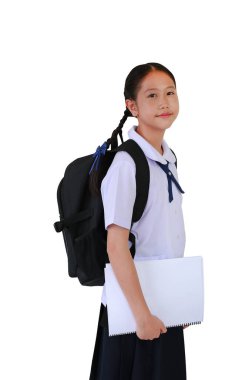 Sırt çantası taşıyan okul üniformalı Asyalı öğrenci portresi beyaz stüdyo arka planında tek başına dururken kitap tutuyor. Kırpma yolu ile resim.