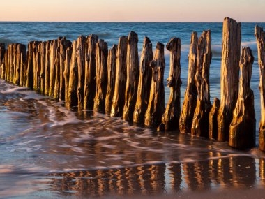 Sunset over the Baltic Sea. View of the old wooden breakwater and its reflection in the water. Mielno, Poland. West Pomeranian. eastern Europe clipart