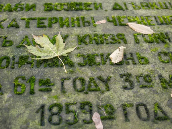 Hoja Otoño Sobre Una Lápida Con Texto Escrito Cirílico —  Fotos de Stock