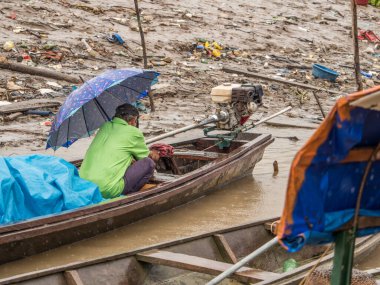 Tabatinga, Brezilya - 15 Eylül 2018: Amazon limanında yağmurlu bir günde teknede şemsiyeli bir adam. Tres Fronteras. Latin Amerika. Amazonia.