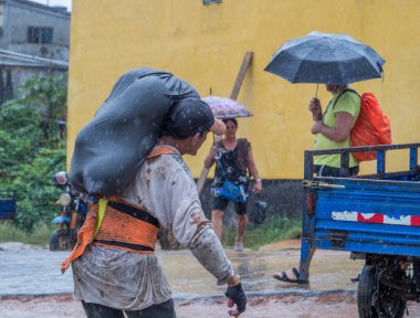 Tabatinga, Brezilya - 15 Eylül 2018: Amazon limanında yağmurlu bir günde meyve dolu siyah çantalı adam. Tres Fronteras. Latin Amerika. Amazonia.