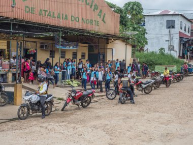 Atalaia do Norte, Brezilya - 21 Eylül 2018: Amazon ormanlarındaki köy sokaklarında mavi okul üniformalı gençler.