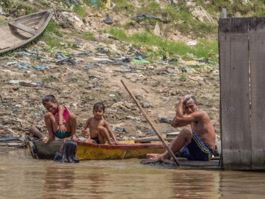Iquitos, Peru - 25 Sep 2018: Aile Itaya Nehri 'nde banyo yapıyor. Arka planda büyük bir kirlilik görülebilir. Amazon 'un düşük su mevsimi. Iquitos Peru 'nun Beln ilçesi