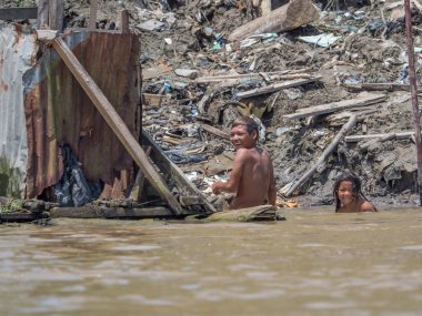 Iquitos, Peru - 25 Sep 2018: Erkekler çantaları kömürle taşıyorlar. Itaya Nehri kıyısında arka planda büyük bir kirlilik görülebilir. Amazon 'un düşük su mevsimi. Iquitos Peru 'nun Beln ilçesi