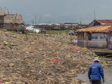 Iquitos, Peru - 25 Sep 2018: Adam Itaya nehrinin kıyısında oturur ve vücudunu suyla serinletir. Arka planda büyük bir kirlilik görülebilir. Amazon 'un düşük su mevsimi. Iquitos Peru 'nun Beln ilçesi