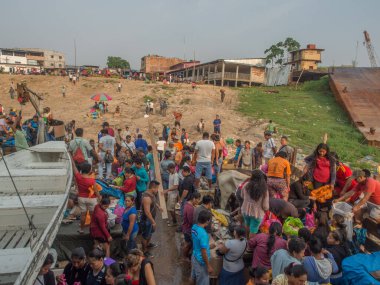 Iquitos, Peru - 21 Sep 2017: Bir kargo gemisindeki yerel halk ve Iguitos 'taki Amazon Nehri üzerindeki bir limanın çamurlu kıyıları.