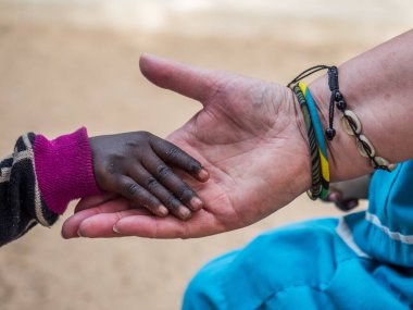Afrikalı çocuk beyaz kadının eline dokunuyor. Çeşitlilik konsepti. Senegal. Afrika.