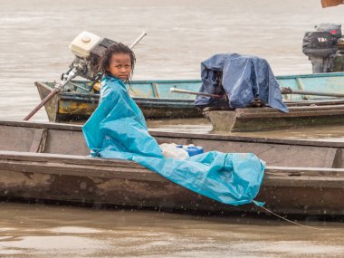 Tabatinga, Brazil - Sep 22, 2018: Girl from the Ticuna tribe on the boat cover with the blue plastic bag   Most numerous tribe in the Brazilian Amazon clipart