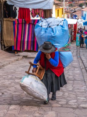 Pisac, Peru - 19 Mayıs 2016: Pisac caddesinde arkasında büyük mavi çantalı kadın. Latin Amerika.