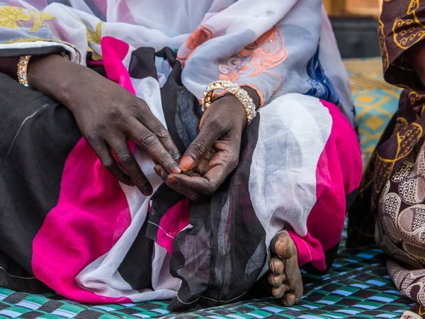 stock image Black well-groomed hands and destroyed foot of an African woman in the colorful boubou. Senegal. Africa.