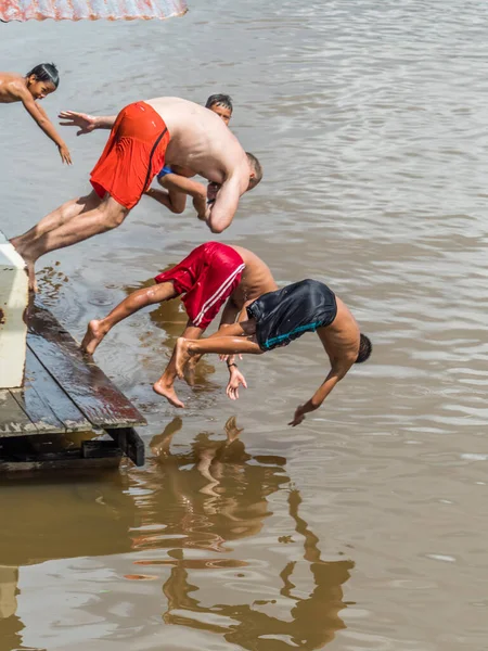 stock image Pebas, Peru - December 04 , 2018: Peruvian children is jumping to the Amazon rover with white, big man. Diversity concept