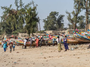 Nianing, Senegal - 2 Ocak 2019: Balıkçılar sahilde duran renkli ahşap balıkçı teknesinden balık topluyor. Afrika