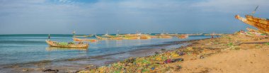 Senegal, Afrika - 26 Ocak 2019: Okyanus kıyısında bir sürü plastik torba. Kirlilik konsepti. Arka planda renkli balıkçı tekneleri. Panoramoc görünümü. Senegal. Afrika.