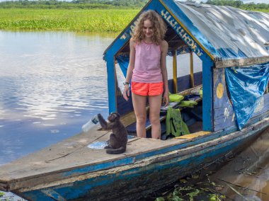 Iquitos, Peru - 15 Mayıs 2016: Fırtınalı bulutların arkasında Amazon nehrinin kıyısında genç bir kadınla tekne bekliyor