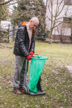 Bahçedeki bahar temizliği sırasında sakallı, olgun bir adam.