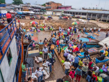 Iquitos, Peru - 14 Mayıs 2016: Bir kargo gemisinde yerel halk kalabalığı ve Iguitos 'taki Amazon Nehri üzerindeki bir limanın çamurlu bir sahili. Amazonia. Güney Amerika.
