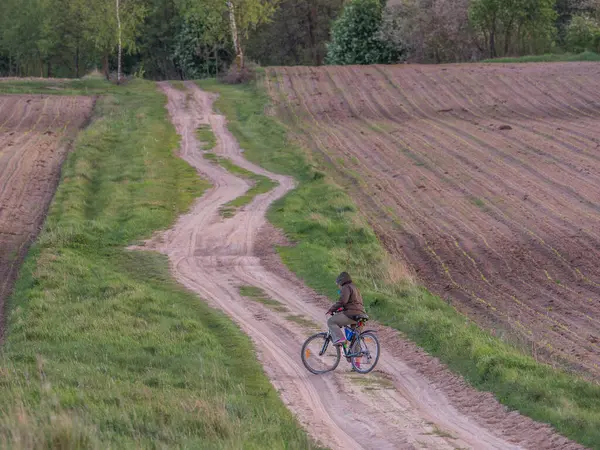 Woman on bicycle on a countryside road. Podlasie. Podlachia. Poland, Europe. The region is called Podlasko or Podlasze.