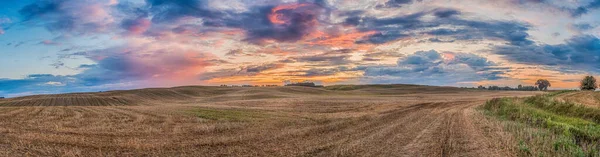 Panoramic view of the hills and fields after mowing the grain during the summer sunset. Warmia and Masuria. Poland