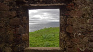 Pencereden bak. Eski Slains Kalesi olarak da bilinen Slains Kalesi, İskoçya 'nın Aberdeenshire şehrinde yıkılmış bir kaledir. Cruden Körfezi 'nin yaklaşık bir kilometre doğusundaki kayalık bir sahilde bulunur ve Kuzey Denizi' ni denetler.