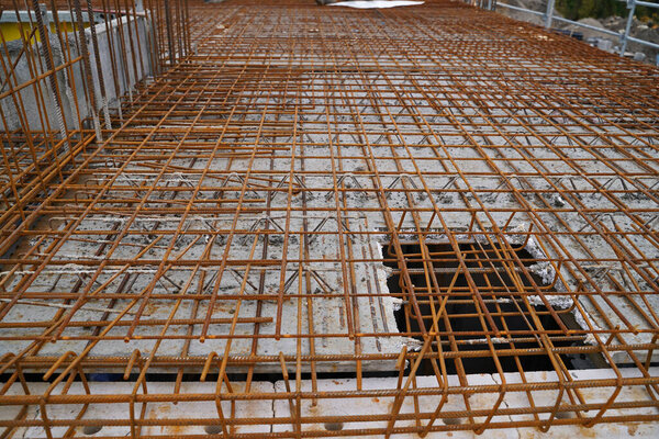 Изготовление арматуры из стали на большой строительной площадке с решетчатой стрелой крана в новом строительстве жилых зданий.