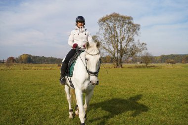 white horse and rider riding on the meadow in Bavaria extra for a photo shoot.