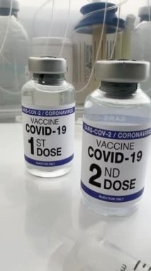 Coronavirus aşısı etiketlenmiş. Etikette birinci, ikinci, üçüncü ve dördüncü doz aşılar var. COVID-19 aşı şişeleri 1., 2., 3. ve 4. aşılar Omikron varyantları için etiketlenmiş. portre biçimi.