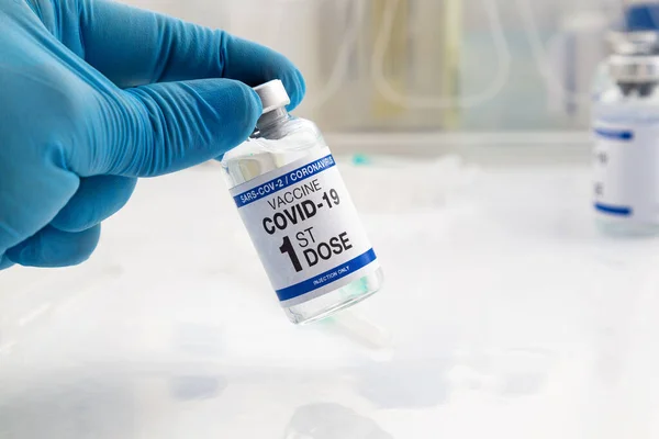 手持用Covid 19疫苗Vial接种疫苗 贴有一剂疫苗 标签上印有头一剂眼镜蛇疫苗名称的Coronavirus疫苗瓶的医生 — 图库照片