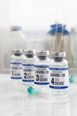 COVID-19 aşı şişeleri 1., 2., 3. ve 4. aşılar Omikron varyantları için etiketlenmiş. Coronavirus aşısı etiketlenmiş. Etikette birinci, ikinci, üçüncü ve dördüncü doz aşı.