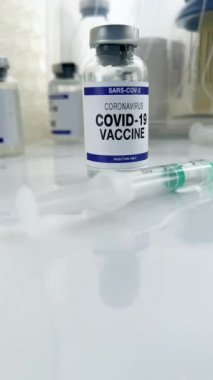 Coronavirus aşısı, şırınga ve diğer Covid-19 aşıları üzerinde çalışma masası. Sars-cov-2 'nin aşı varyantları için şişe içeren tıbbi tezgah