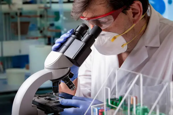 stock image Researcher microbiologistanalyzing a slide containing a blood sample in microscope in a research laboratory. Laboratory scientist working with a microscope in microbiology laboratory.