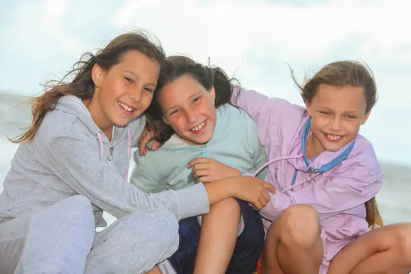 Bir grup neşeli çocuk dışarıda oturuyor ve sarılıyorlar.