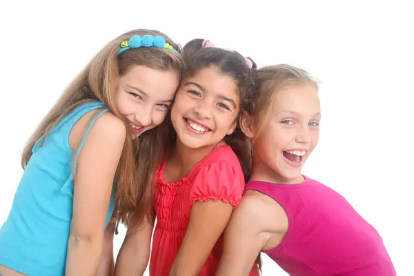 Renkli kıyafetler içinde, beyaz arka planda sarılıp gülümseyen çok ırklı bir grup neşeli kız.