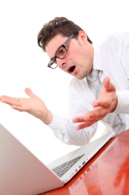 Stresli genç adam umutsuzca dizüstü bilgisayar ekranına bakıyor.  