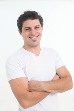 Beyaz arka planda beyaz tişörtlü yakışıklı, neşeli genç adam.