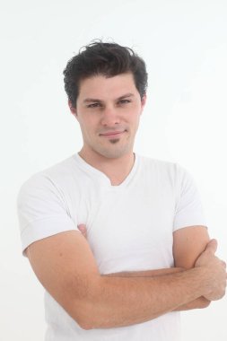 Beyaz arka planda beyaz tişörtlü yakışıklı, neşeli genç adam.