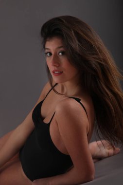 Stüdyoda siyah takım elbiseli, esmer, genç bir bayan.