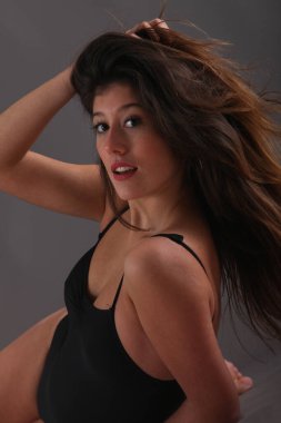 Stüdyoda siyah takım elbiseli, esmer, genç bir bayan.